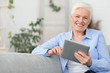 © Prostock-studio - Smiling beautiful senior woman using digital tablet at home, empty space, close up