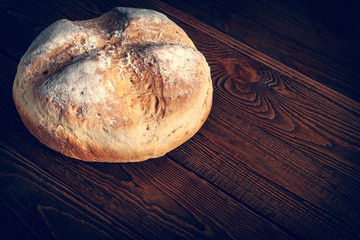 Homebaked bread. Wheat fresh bread on a wooden background. Homemade baking.