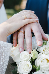 Wall Mural - bride and groom demonstrate wedding rings over a bride's bouquet of white roses