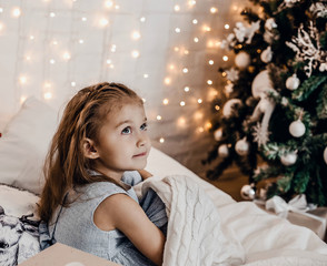 Wall Mural - Little beautiful girl under the covers near the Christmas tree