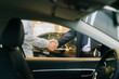 © dikushin - Buyer of car shaking hands with seller in auto dealership, view from interior of car. Close-up of handshake of business people. Concept of choosing and buying new car at showroom.