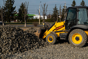 Yellow wheel loader Excavator machine working at construction site with gravel. Preparing of the fundament for a asphalting. Road construction site. Building of a parking.