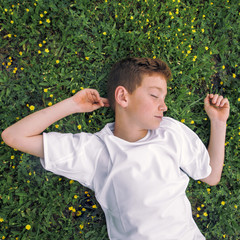 sleepy little boy lying in a bed of clover
