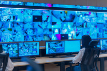 Group Of Security Data Center Operators (administrators) Working In A Group At A CCTV Monitoring Room While Looking At Multiple Monitors ( Computer Screens)