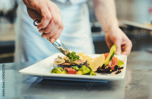 Fotografía Proud chef garnishing an almost finished dish in the restaurant with leave