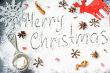 Directly Above Shot Of Christmas Greetings On Flour With Decoration And Spices At Table