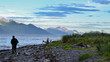 © Jordan Feeg - Person walking along rocky beach shoreline in Alaska mountain landscape background. Alaska tourism in the summer