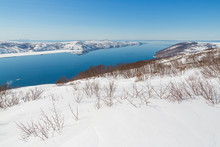 Beautiful View Of The Sea Bay And The Coast. The Slopes Of The Hills Are Covered With Snow. Spring In The North-east Of Russia. Nagaev Bay, Sea Of ​​Okhotsk. Magadan Region, Siberia, Russian Far East.