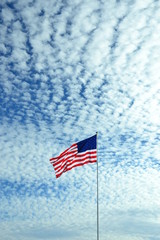 American flag flying in wind, beautiful clouds pattern background.