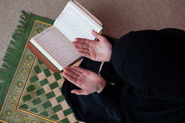 Wall Mural - Middle eastern woman praying and reading the holy Quran