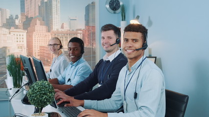 Wall Mural - Diverse team of call center customers looking to the camera and smiling after talking to the international clients on phones