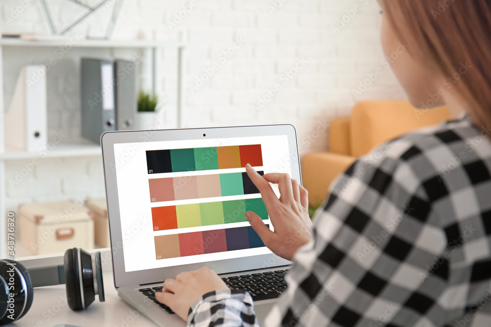 Young female designer with laptop working at home