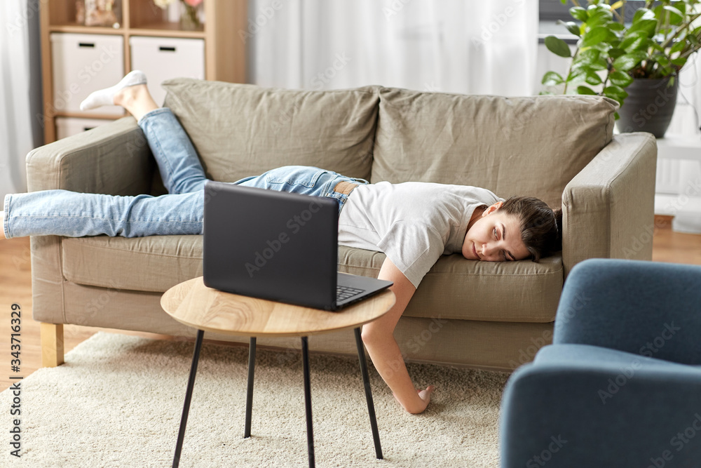 people, boredom and depression concept - bored or lazy young woman with laptop computer lying on sofa at home - obrazy, fototapety, plakaty 