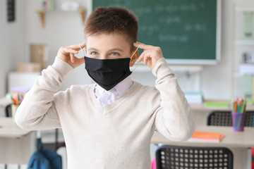 Sticker - Little schoolboy in protective mask in classroom. Concept of epidemic