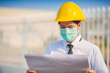 Businessman holding paperwork planing blueprint and use surgical mask protect working on construction site