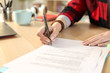 © PheelingsMedia - Student hands signing contract sitting at home