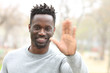 © PheelingsMedia - Happy black man waving hand looking camera