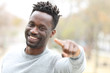 © PheelingsMedia - Happy black man pointing and looking camera in a park
