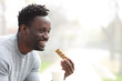 © PheelingsMedia - Happy black man having coffee and snack bar in a park