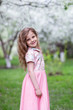 © Evgenia - A little girl in a pink dress in a blooming garden