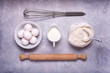 in the kitchen on the gray textured background, some utensils, flour, milk and eggs ready for the preparation of homemade culinary recipes