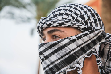 the man’s face is hidden behind the keffiyeh