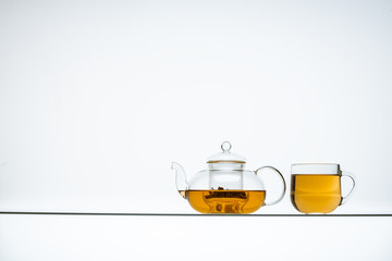 glass teapot and cups with hot tea on table, close view    