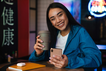 Poster - Photo of asian woman using mobile phone and drinking coffee in cafe