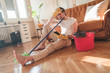 © Teodor Lazarev - Handsome man cleaning his house with mop and plastic bucket, he working hard