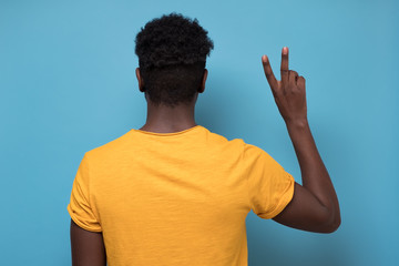 African american man showing two finger scissors gesture turning back