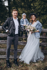 stylish family in the mountains. a guy in a leather jacket, a girl in a wedding dress and a hat with