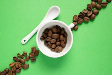 white cup and spoon on a green background, coffee grains. Good morning concept