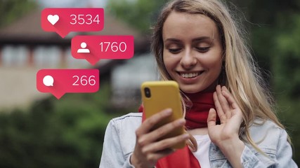 Portrait of young woman wearing in the red scarf using app on smartphone standing near a country house. Animation with user interface with follower, comments, likes counting bubble from smartphone