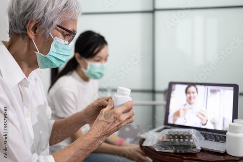 Sick senior woman making video call with doctor on laptop computer while stay home,elderly patient ask a doctor about illness and medicine,online consultation during the Coronavirus,Covid-19 pandemic