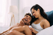 © LIGHTFIELD STUDIOS - Woman smiling and hugging excited man on bed in bedroom
