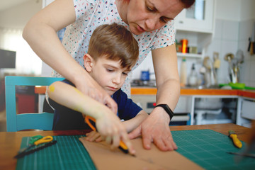 Wall Mural - Mother helping son to cut cardboard, quarantine project