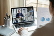 © fizkes - Back view of female employee sit at desk talk on video discuss statistics call with diverse colleagues, businesspeople have webcam conference online briefing or meeting on laptop, teamwork concept