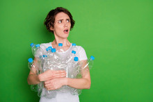 Reduce Reuse Recycle. Photo Of Beautiful Lady Hold Many Plastic Bottles Angry Face Carry Trash Recycling Service Look Side Empty Space Displeased Isolated Green Color Background