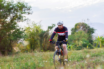 Asian men ride bicycles for exercise in a meadow. Sport and active life concept.