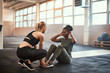 Young woman laughing while doing sit-ups with a  friend