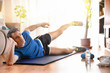 © Davizro Photography - Man doing leg exercises lying on mat in living room