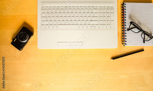 Photographie Laptop, camera, notebook and pen on top of a wooden desk in an office