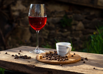 Still life with glass of red wine, coffee cup, beans  in the sun