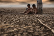 The boy sat on the arid ground, waiting for rain. Due to global warming Global warming and climate change concepts