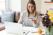 Photo of smiling woman using laptop while holding credit card