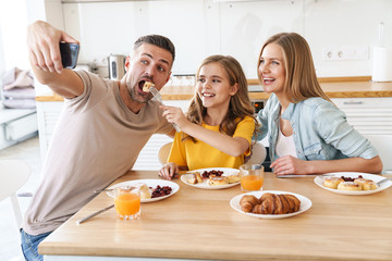 Wall Mural - Photo of funny taking selfie on smartphone while having breakfast