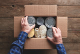 Fototapeta  - a person packing a donation box with food items