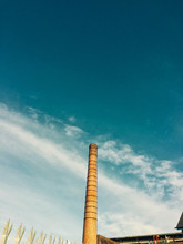Low Angle View Of Smoke Stack Against Blue Sky