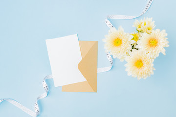 Wall Mural - mockup white wedding invitation and envelope with flowers in a vase on a blue background