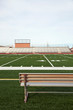© David Engelhardt/Tetra Images - American football field with bench in foreground and empty bleachers in background